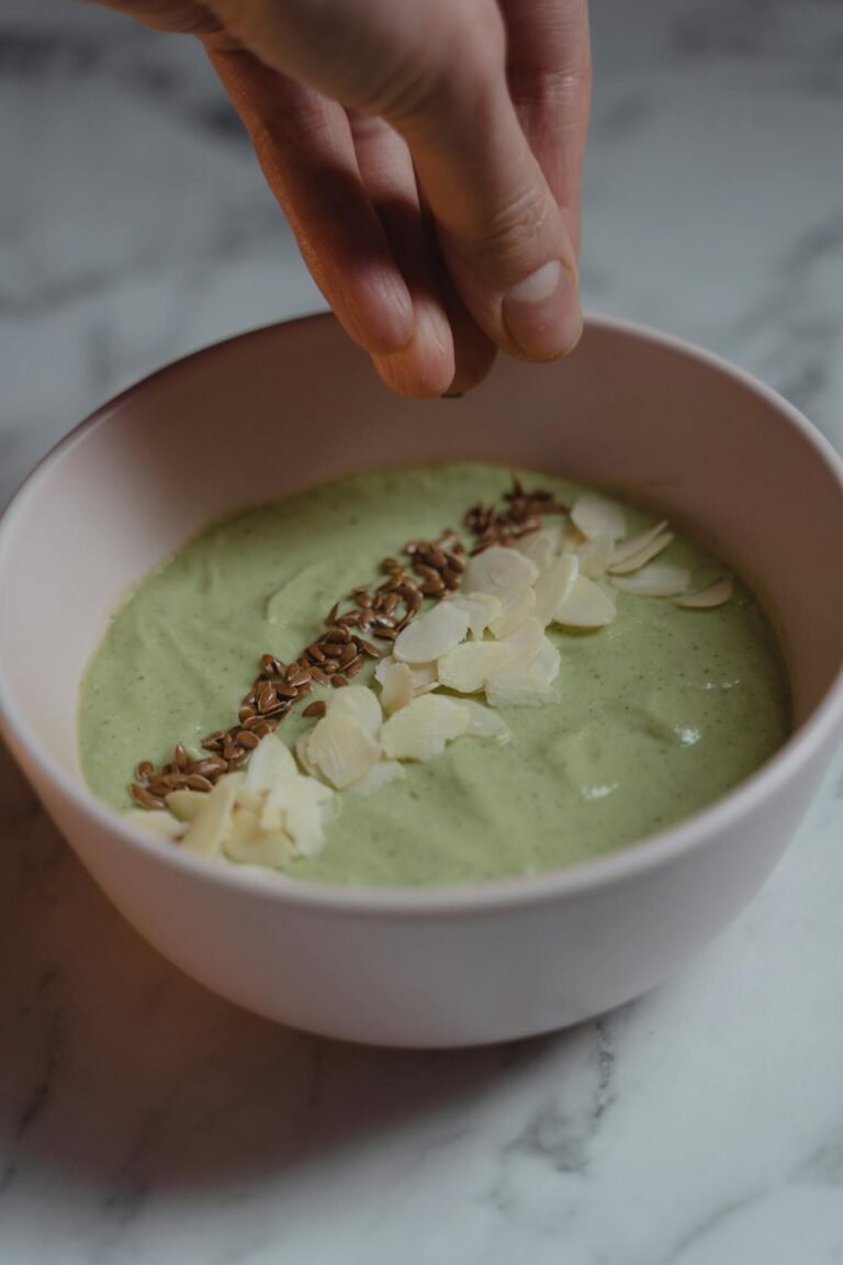 A nutritious green smoothie bowl topped with almonds and seeds, perfect for a healthy breakfast.