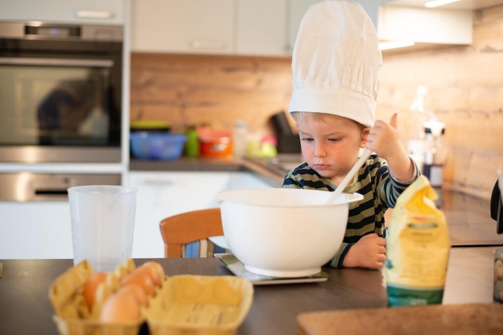 Kid baking low-calorie pancakes in the kitchen
