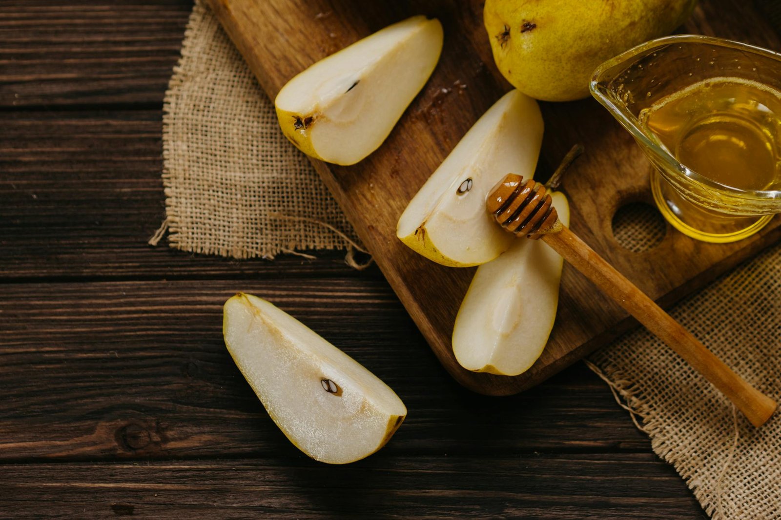 Fresh sliced pears with honey on a wooden board create a rustic healthy dining mood.