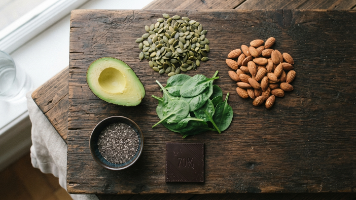 Magnesium for sleep on keto diet food board with pumpkin seeds spinach and avocado